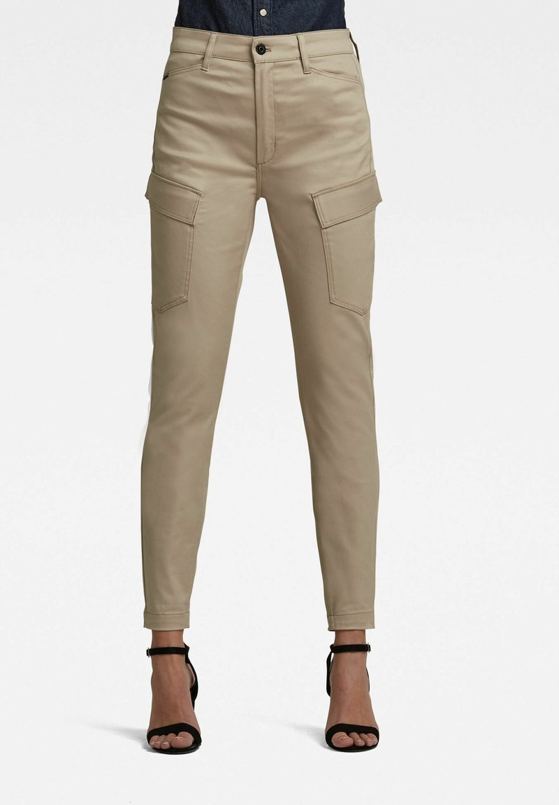 Pantalon cargo beige avec jambes fuselées, doté de quatre poches, passants pour ceinture et une fermeture à bouton. Le matériau semble lisse avec une légère brillance.