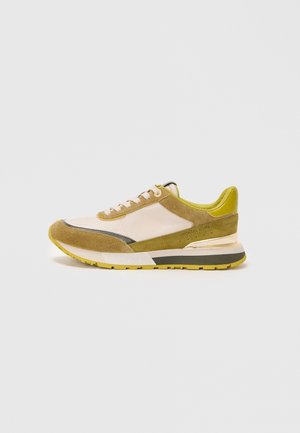 Niskie sneakersy z beżowej skóry z oliwkowymi zamszowymi nakładkami, jasnospodzącą zieloną wyściółką, białymi sznurowadłami i gumową podeszwą z żółtym bieżnikiem.