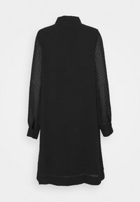 Svart klänning med långa genomskinliga ärmar, texturerat prickigt mönster, krage med knappar och en avslappnad passform. Nederkanten är något rundad.