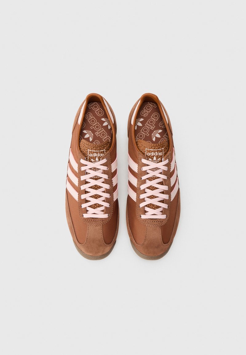 Brown adidas sneakers with pink stripes and laces, branded insoles, laid side by side on a light gray background.