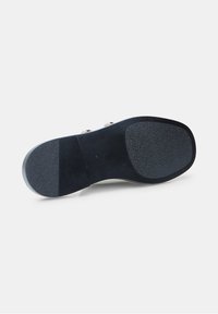 Suela de zapato de ante negro con secciones de goma texturizada, cuenta con un tacón ligeramente elevado y un centro liso con detalles en relieve.