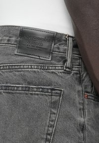 Γκρι τζιν από τζην ύφασμα με σκούρο δερμάτινο ταμπελάκι με την ένδειξη "Abercrombie & Fitch". Διαθέτει ραμμένες τσέπες και μεταλλικές λεπτομέρειες.