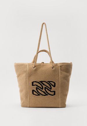 Beige kudumoodne kott musta tikitud sõlme disainiga, kaks käepidet, avatud ülemine osa ja tekstureeritud võrkkangas. Sobib igapäevaseks kasutamiseks.