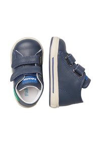 Dětské tmavě modré kožené tenisky s dvojitými suchými zipy a bílými gumovými podrážkami, zobrazené z vrchu a z boku.