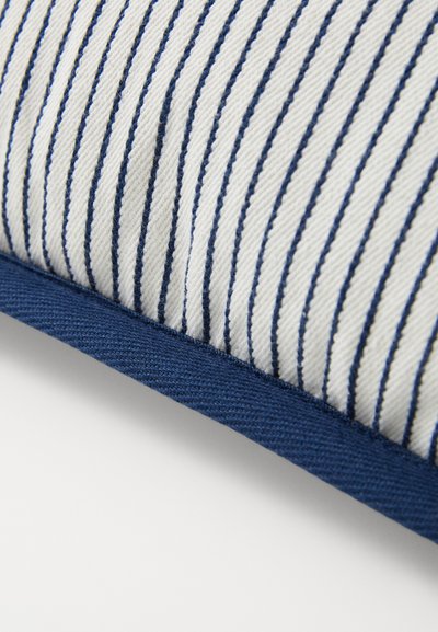 Dryžuotas stačiakampis pagalvėlė su kreminiu fono spalva ir tamsiai mėlynomis juostomis, akcentuota tamsiai mėlynu audinio rėmeliu ir tekstūruota paviršiumi.