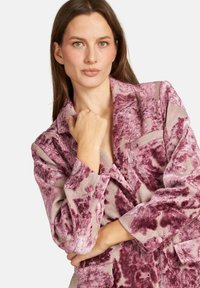 Blazer texturizado en un patrón floral rosa y burdeos, con cuello de muesca, bolsillos frontales y un corte relajado. Tela suave y esponjosa.