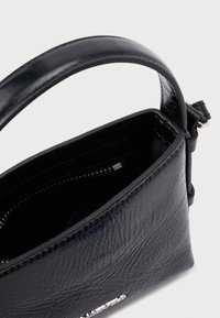 Melna ādas somiņa pāri plecam ar stingru formu, gludu tekstūru, rāvējslēdzēja nodalījumu un īsu, izturīgu rokturi.