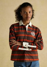 Gestreiftes Langarm-Poloshirt in Braun und Orange mit weißem Kragen und gesticktem Logo, ausgestattet mit knöpfbaren Manschetten und einem geraden Saum.