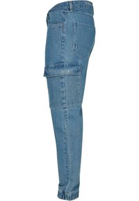 Lyseblå denim cargo bukser med sidelommer, en tapered ben og en opkrøllede kant. Materialet har en blød, let slidt tekstur.