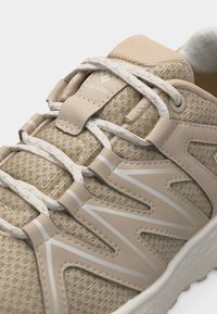 Μπεζ πεζοπορικό αθλητικό παπούτσι με αναπνέον δίχτυ, κορδόνια με σχέδια, υποστηρικτικές συνθετικές επενδύσεις και μαλακή σόλα, με το λογότυπο της Columbia.