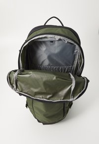 Zaino verde e nero con grande apertura, dotato di rivestimento grigio e una tasca esterna. Realizzato in tessuto resistente con forma strutturata.