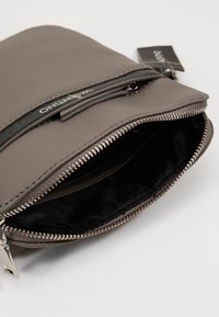 Gray fabric pouch with a black zipper and silver hardware. The interior is lined in black, showcasing dual compartments and textured fabric.