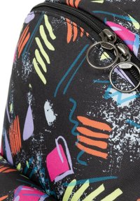 Černý látkový batoh s barevným abstraktním vzorem a geometrickými tvary. Jsou viditelné dva kulaté táhly zipu.