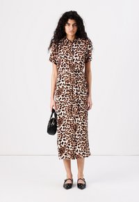 Abito midi con stampa leopardata, maniche corte, apertura frontale con bottoni e vita aderente. Tessuto morbido, colletto rotondo, abbinato a una borsa nera e scarpe.