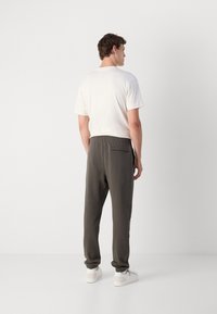 Grijze joggers met elastische tailleband en boorden, met een achterzak, gecombineerd met een plain witte shirt met korte mouwen en witte sneakers.