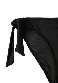 Svart bikinitrosa med knytning på ena sidan, tillverkad av slät tyg med sömlös finish och minimal täckning.