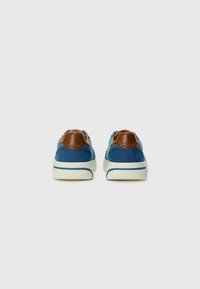 Baskets en denim avec des accents en cuir marron et une semelle en caoutchouc blanche. Elles présentent un bout arrondi et des détails cousus à l'arrière.