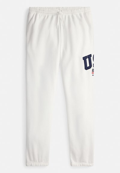 Weiße Jogginghose mit elastischem Bund, versehen mit marineblauer "USA"-Beschriftung und einem kleinen Flaggenakzent am linken Bein. Glatte Textur.