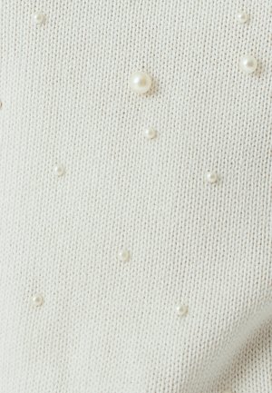 Cremfarbener Strickstoff mit verstreuten Perlenakzenten in verschiedenen Größen, die der Gesamtgestaltung Textur und Detail verleihen.