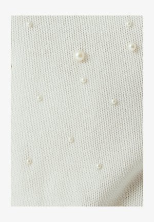 Kermainen neulontakangas, jossa on hajallaan erilaisista koista koostuvia helmikoristeita, lisäten tekstuuria ja yksityiskohtia kokonaisdesigniin.