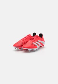 Scarpe da calcio rosse con un design elegante, dotate di una tomaia testurizzata, dettagli neri e strisce bianche sui lati. Suola chiodata per una migliore aderenza.