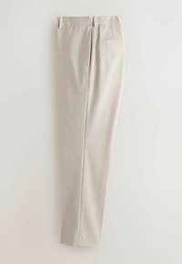 Pantalon beige sur mesure avec passants de ceinture, poche à fente arrière, et un tissu subtilement texturé, présenté plié en longueur sur un fond clair.