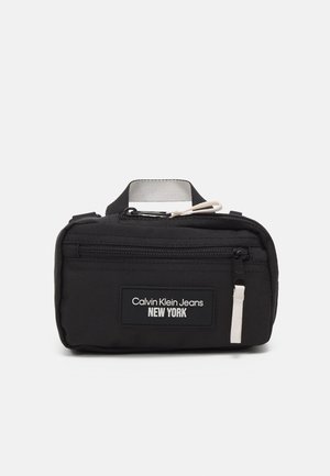 Pochette noire Calvin Klein Jeans avec poche zippée à l'avant et étiquette blanche avec le texte « Calvin Klein Jeans New York .»