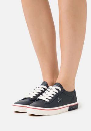 Navy leather sneakers with white laces, red accent stripe on the sole, and a logo on the side. Low-top design with a round toe.