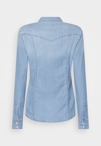 Hellblaues Jeanshemd mit langen Ärmeln, spitzem Kragen und einem geschwungenen Passe-Naht. Verfügt über Knopfmanschetten und Nahtdetails.