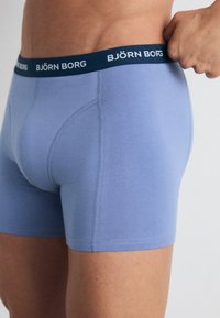 Svetlo modri bombažni bokserice z mornarsko modrim elastičnim pasom, na katerem je napisan tekst "BJÖRN BORG". Imajo ploskate šive in prilegajočo zasnovo.