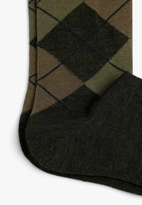 Groene en bruine argyle-gepatroneerde sokken met een gestructureerde brei, featuring donker groene accenten bij de teen en de boorden.