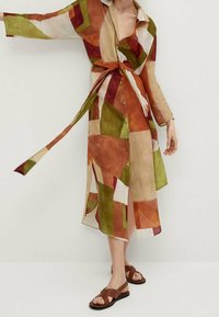 Robe chemise en lin multicolore avec motifs géométriques en orange, vert et beige. Dotée d'une taille ceinturée et de fermetures à boutons.