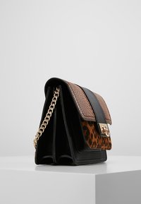 Sac à main en cuir avec des sections à imprimé léopard noir et marron. Il est doté d'une bandoulière chaîne dorée et d'un design rectangulaire structuré.