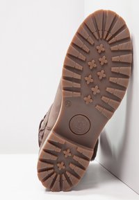 Suela de bota de goma marrón con un patrón de banda de rodadura que presenta estrías texturizadas y acentos elevados. Incluye marca de tamaño 39.