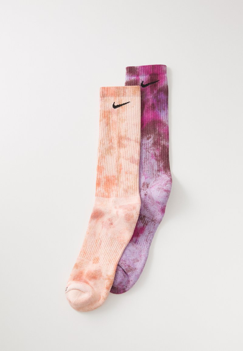 Nike zoknik, amelyek őszibarack és lila árnyalatú batikolt mintával, bordázott textúrával és fekete logókkal rendelkeznek a felső részen.