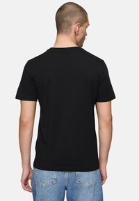 T-shirt nera a maniche corte realizzata in cotone liscio. Presenta un collo rotondo e un design semplice e pulito, privo di qualsiasi marchio o motivo visibile.