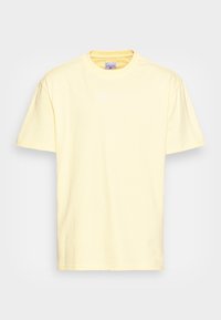 Ljust gult bomull t-shirt med korta ärmar, rund halsringning och subtil vit logotyp tryckt på framsidan. Slät textur och avslappnad passform.