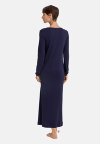 Långärmad nattsärk i marinblått, tillverkad av mjukt tyg. Har en avslappnad passform, golvlång design och en vid rund halsringning. Inga mönster.