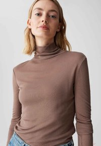 Maglione a collo alto marrone in materiale morbido e elastico, con maniche lunghe, design aderente e texture liscia, abbinato a pantaloni in denim.