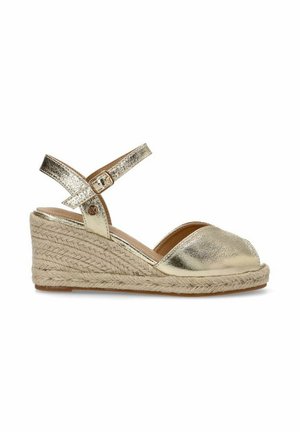 Espadrilles de cuña metálica dorada con punta descubierta, correa ajustable en el tobillo y suela de plataforma de yute trenzado. Textura suave en general.