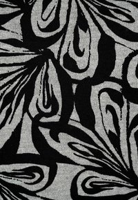 Schwarz-blühendes Muster auf einem strukturierten weißen Stoff, mit kräftigen, wirbelnden Formen und scharfen Konturen, die einen auffälligen Kontrast erzeugen.