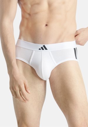 Slip bianchi da uomo realizzati in un tessuto liscio, con una vita a righe nere e un design aderente per comfort e supporto.