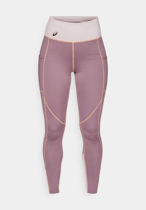 Sima, rugalmas anyagból készült leggings világos lila színben, bézs részletekkel. Magas derékú és oldalsó zsebekkel rendelkezik.