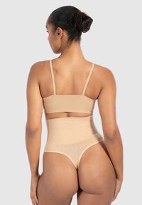 Nude naadloze bh met hoge taille slipset, met verstelbare bandjes, geribbelde textuur en een gladde afwerking. Achteraanzicht weergegeven.