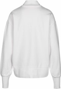 Sudadera blanca con cuello alto, hombros caídos y puños acanalados. Textura suave con un diseño sencillo y sin adornos.