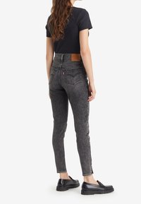 Černé džíny s vysokým pasem, slim fit, viditelným švem, dvěma zadními kapsami a koženou značkovou nášivkou na pásku.