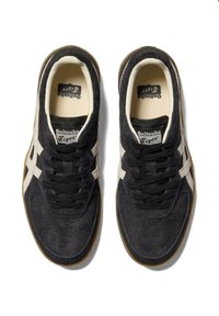 Black suede sneakers with white leather accents, featuring a textured upper, lace closure, and a classic low-profile design.