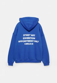 Felpa blu con cappuccio, con testo bianco: "STWD™ ART EXHIBITION APPUNTAMENTO SOLO CIRCA 91" sul retro. Tessuto morbido e vestibilità casual.