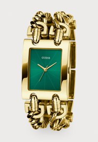 Gold-tone watch with a square green dial, linked bracelet featuring chain accents, and minimalist design. Brand name "GUESS" displayed on the dial.
