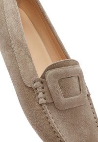 Mocassini in scamosciato di un beige chiaro con un accento a fibbia quadrata, dettagli cuciti e una fodera interna liscia. Design classico slip-on.
